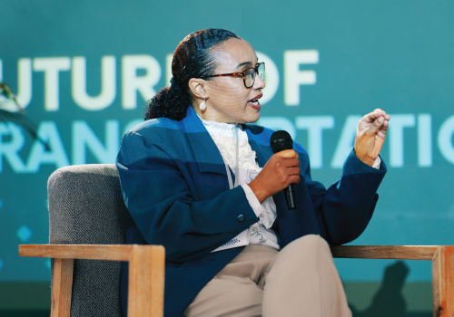 A woman sat on a chair talking into a microphone explaining how communicating your business' sustainability efforts is of the utmost importance for transparency and building an environmentally-conscious future.